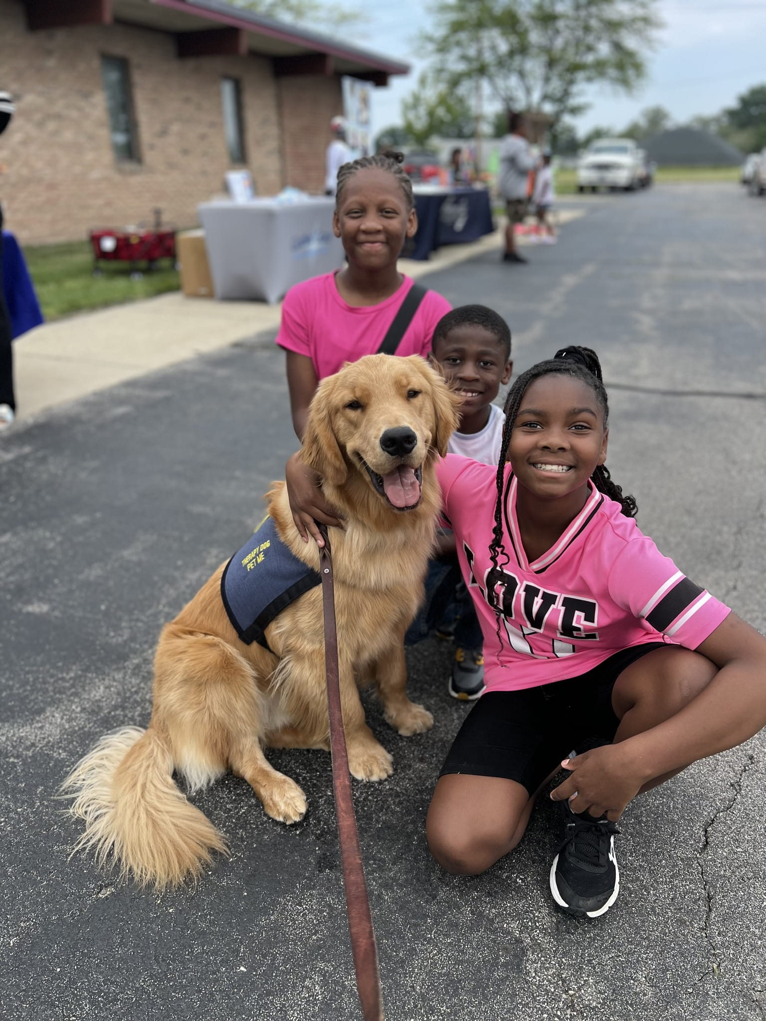 Three children posing with MSP Therapy Dog. 