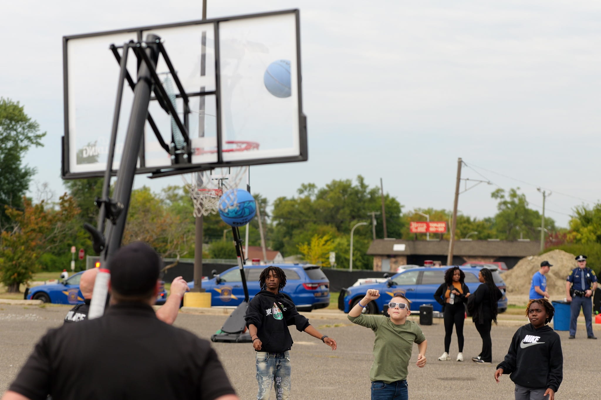Several children playing basketball outdoors. 