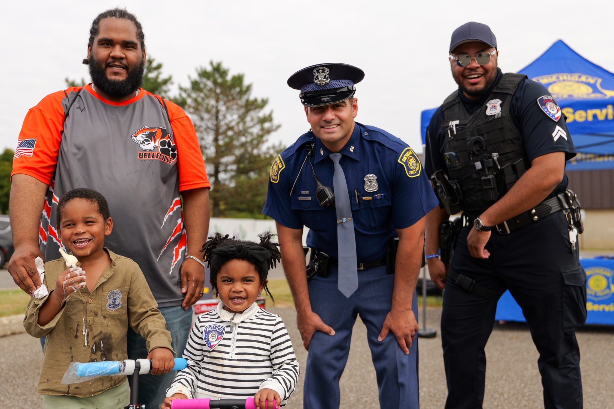 Two police officers standing with a man and two young children. 