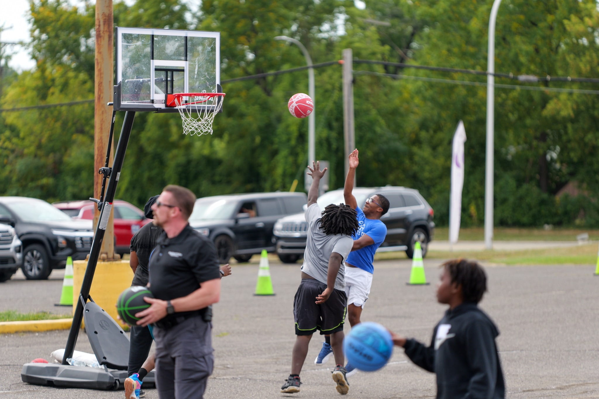 Police officers and community members playing basketball outdoors. 