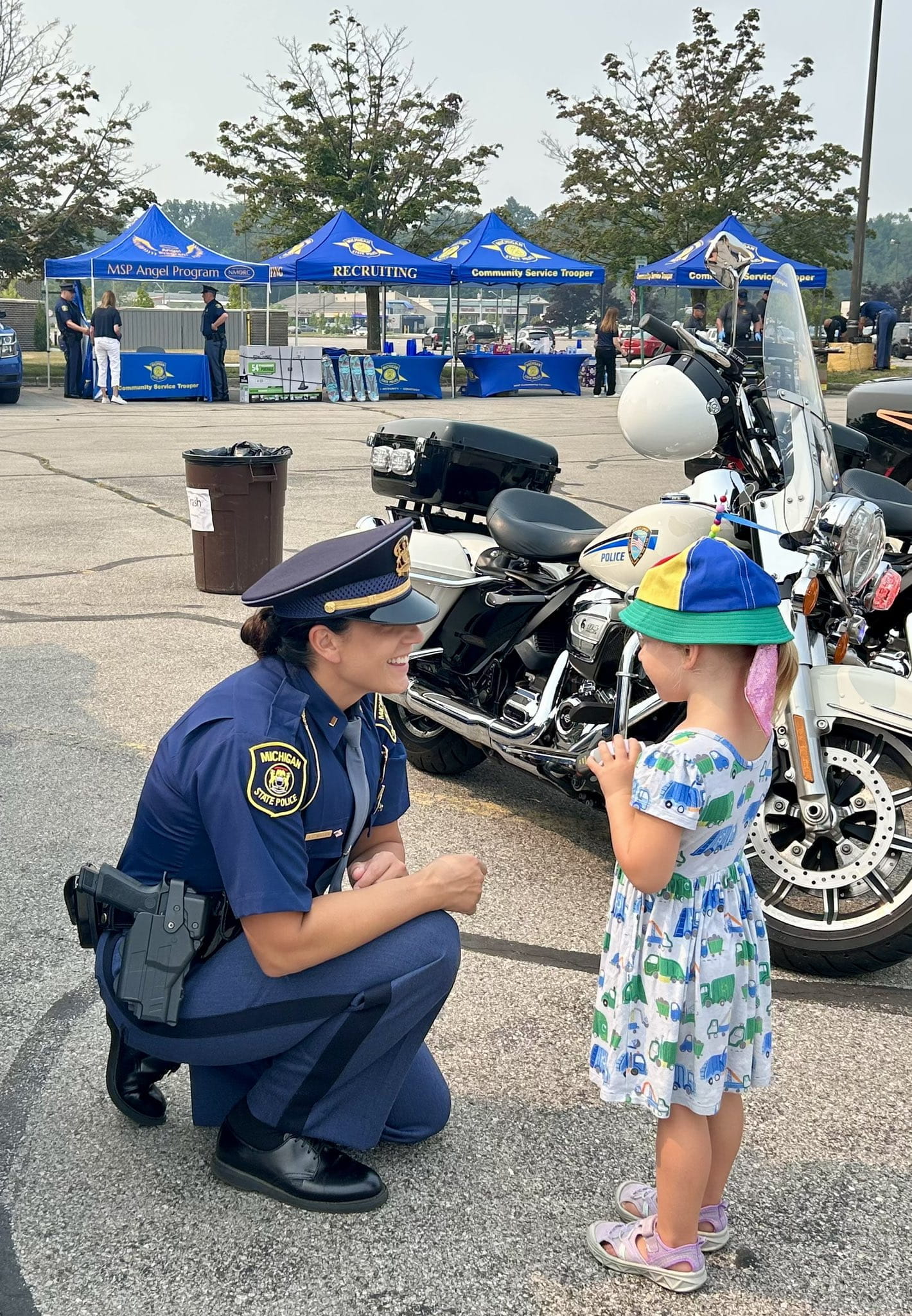 Female police officer kneeling to speak with young girl. 