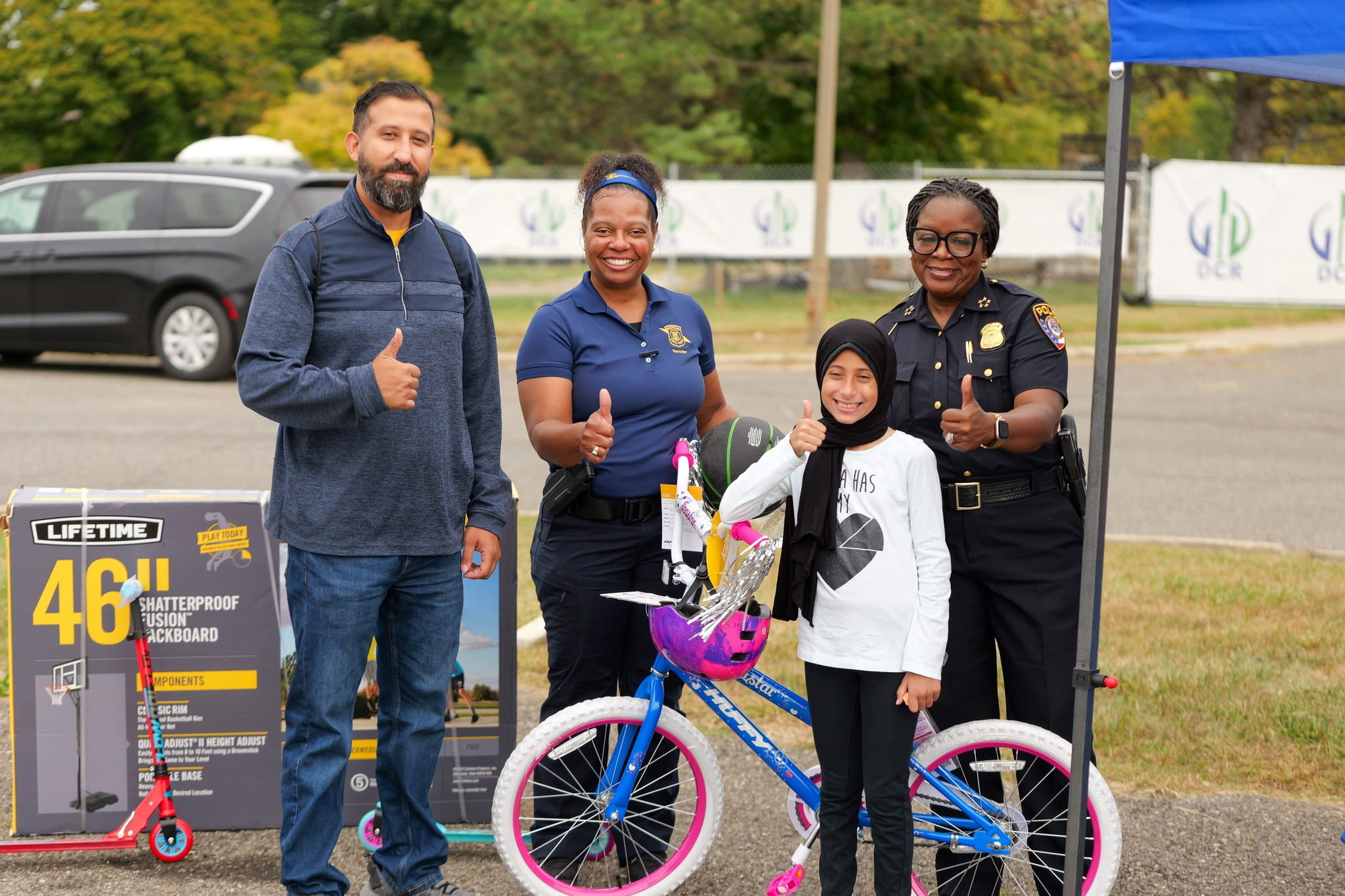 Two police officers with a man and child with a bicycle at an outdoor community event. 