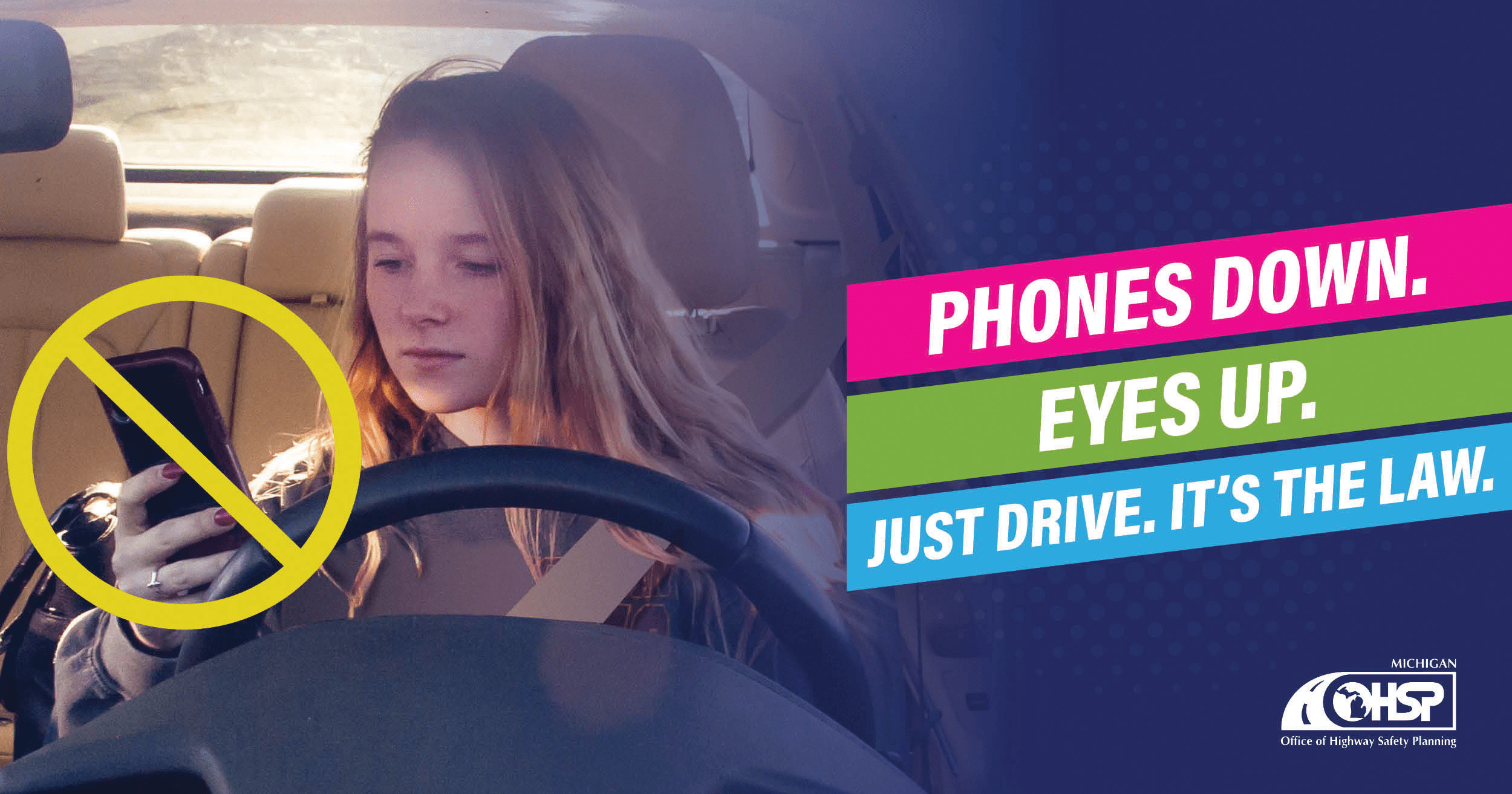 girl behind the wheel of vehicle looking at cell phone