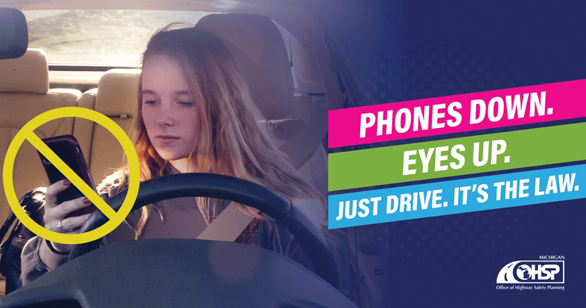 girl behind the wheel of vehicle looking at cell phone