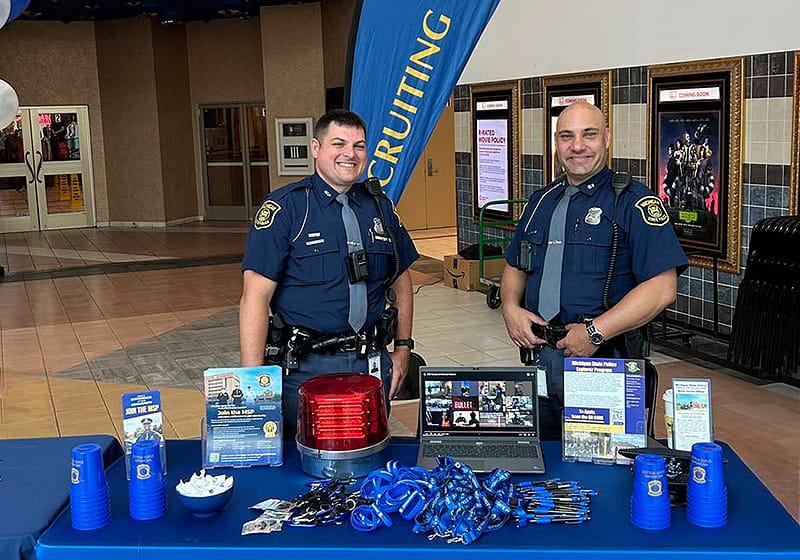 Two MSP troopers standing at a recruiting table. 