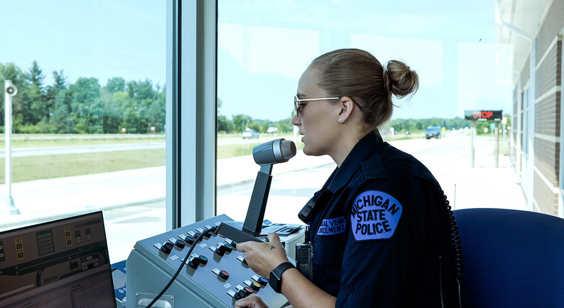Female motor carrier officer working inside weigh station.