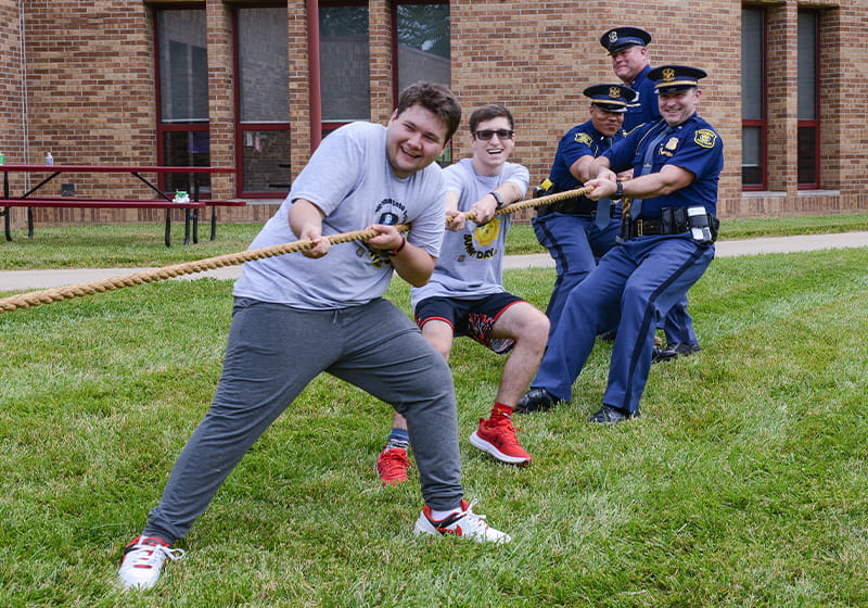 Kids and troopers playing tug of war outside