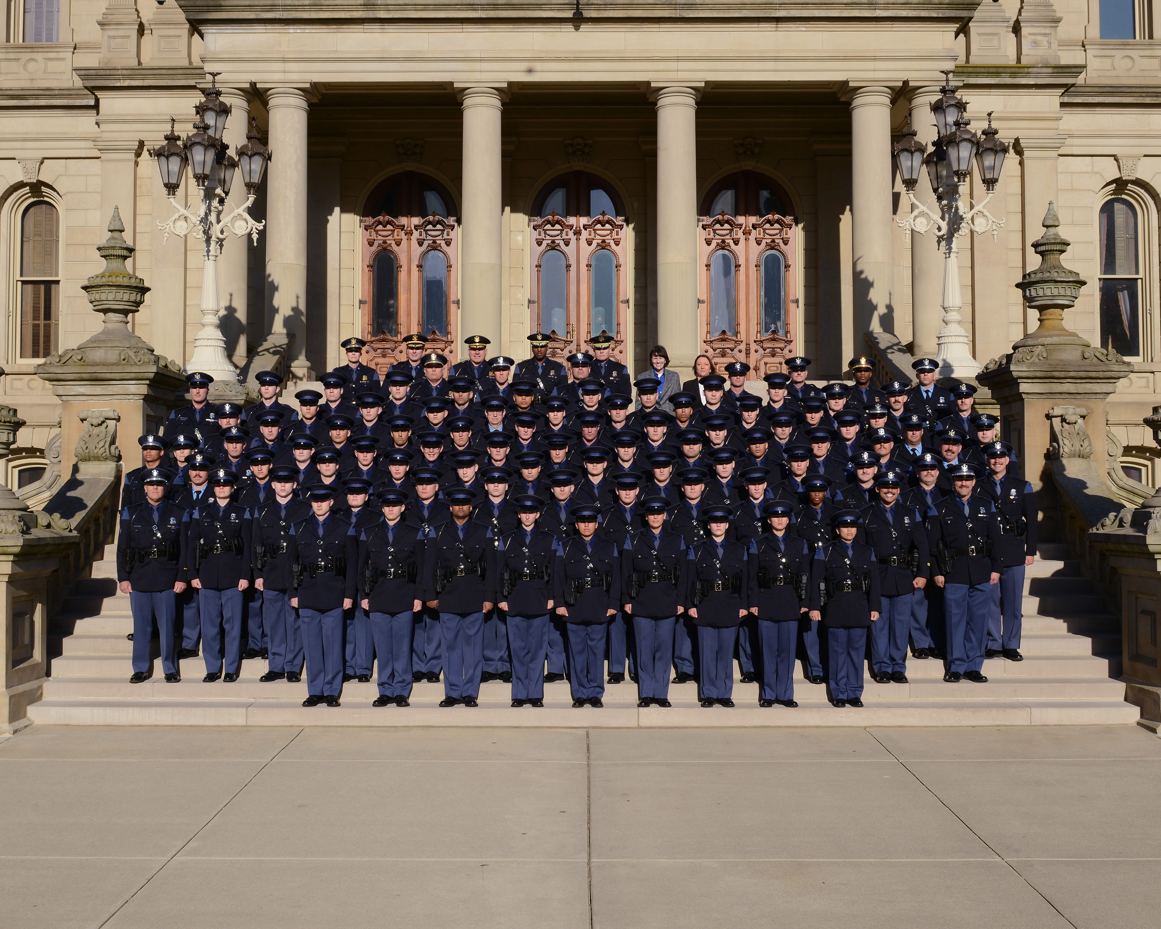 Members of the 150th Trooper and 28th Motor Carrier Officer Recruit Schools standing outside on the Capitol steps with command staff members