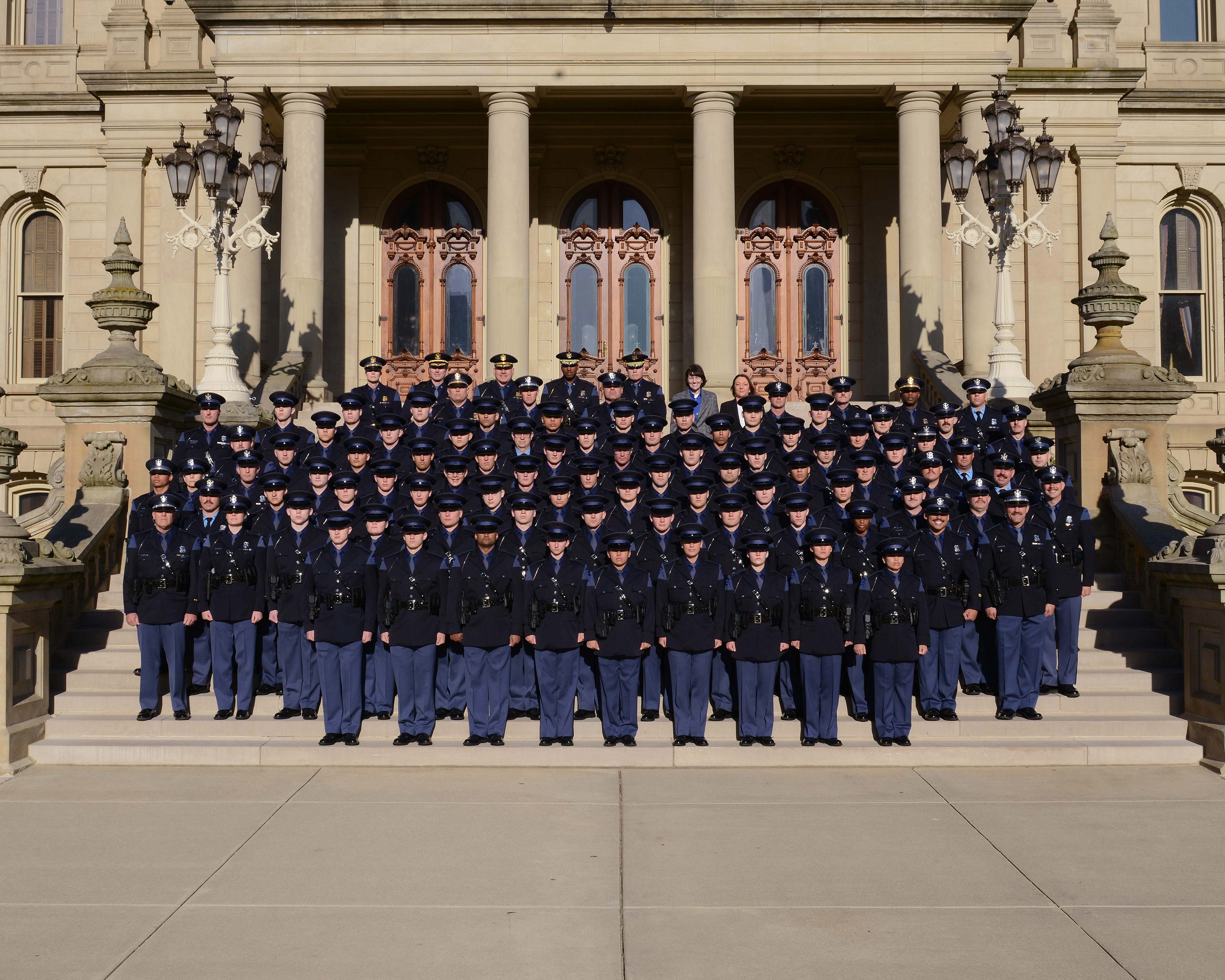 Members of the 150th Trooper and 28th Motor Carrier Officer Recruit Schools standing outside on the Capitol steps with command staff members