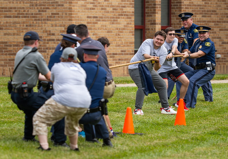 Troopers play tug-of-war with youth at 2024 Sunny Day Camp in Attica, Michigan. 