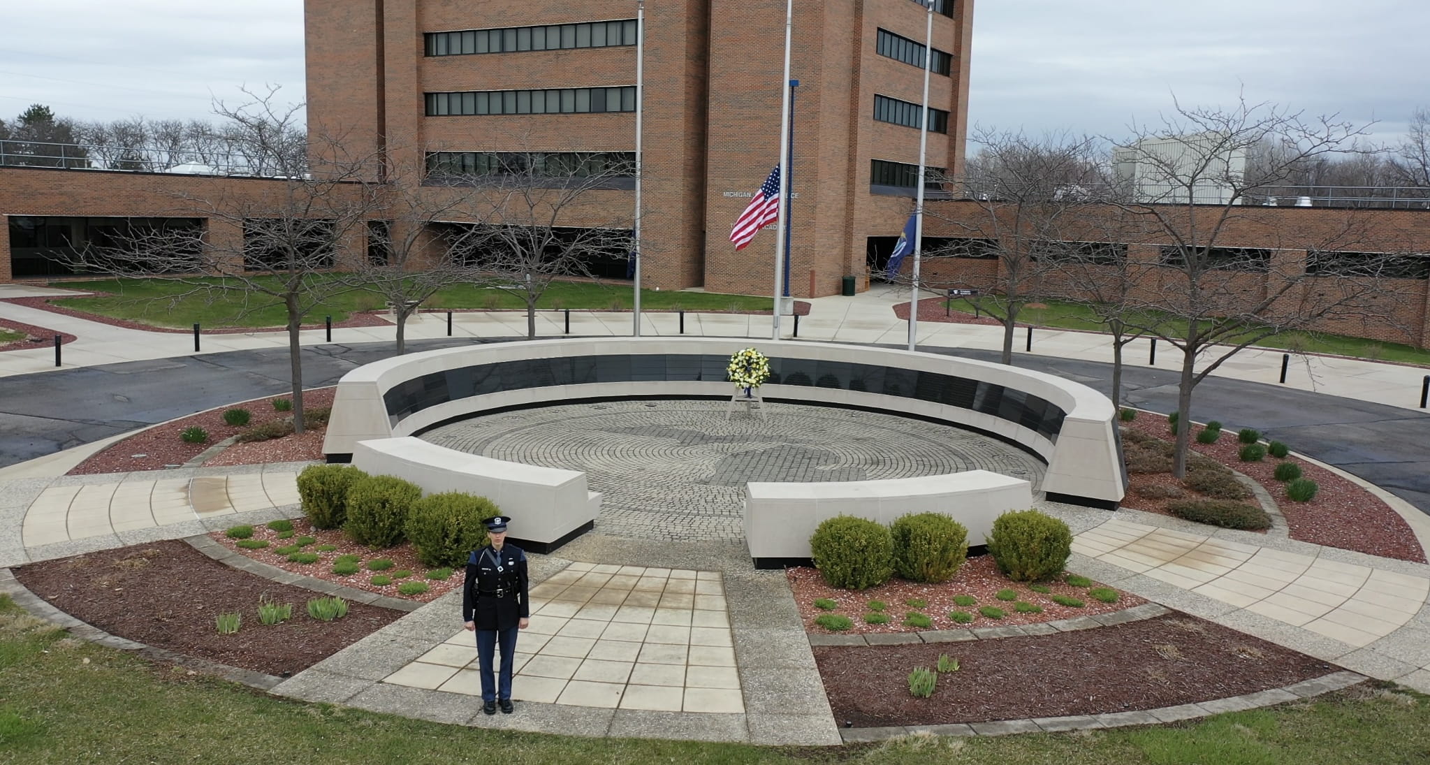 An MSP trooper stands at attention at the Fallen Trooper Memorial on the front lawn of the MSP Training Academy in Dimondale