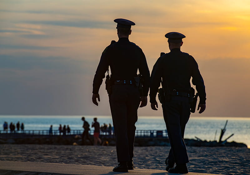 MSP troopers in silhouette with sunset over lake in background. 