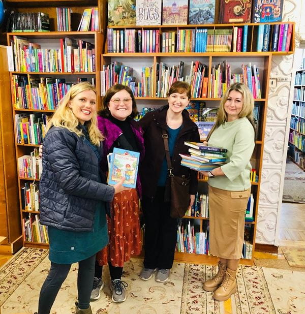 Four people standing in front of a book shelf and holding books