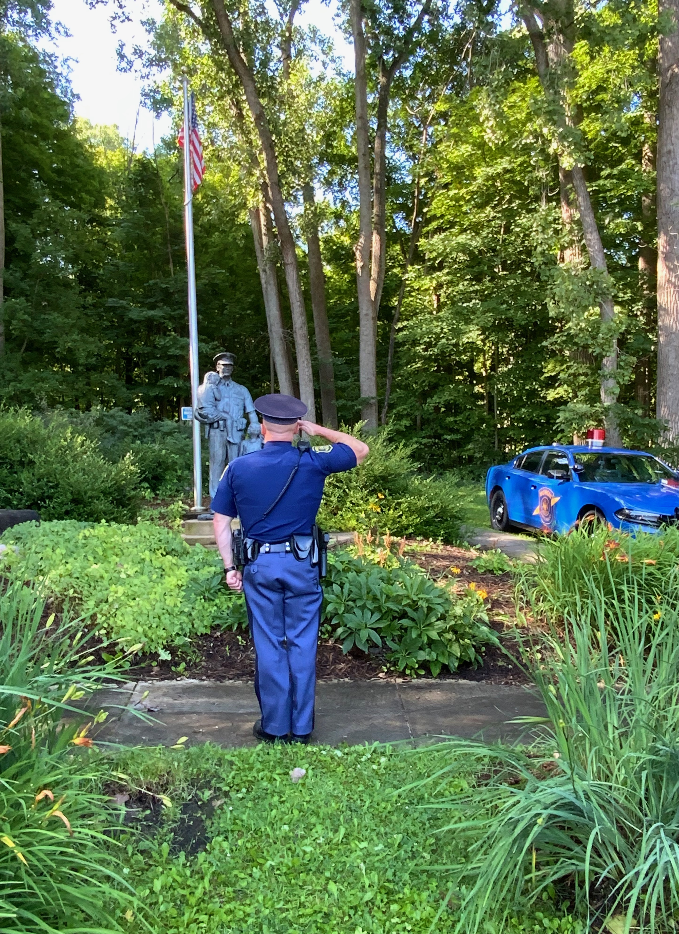 An MSP trooper salutes a bronze statue named for fallen Tpr. Kevin M. Marshall in the eponymous Marshall Memorial Park in Newaygo