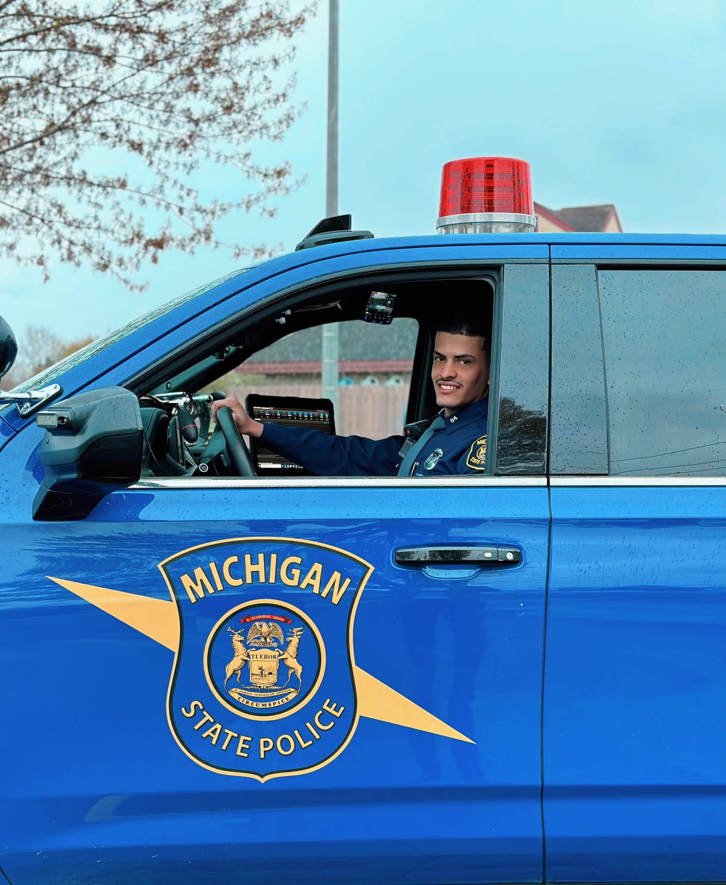 Photo of Tpr. Bakeel Abdullah sitting in an MSP patrol vehicle 