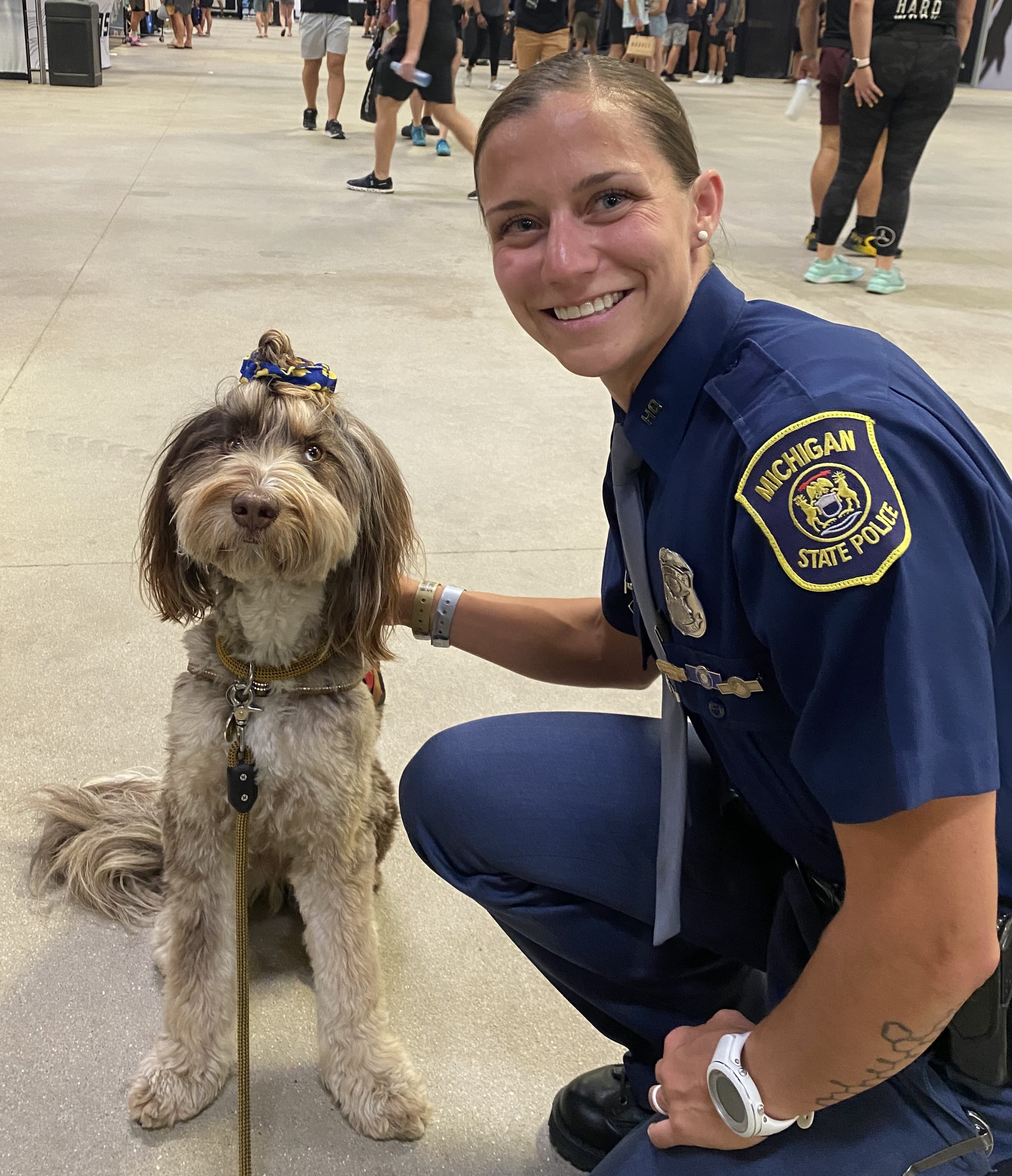 Photo of Tpr. Melissa Beafore crouching down next to a dog at an indoor recruiting event