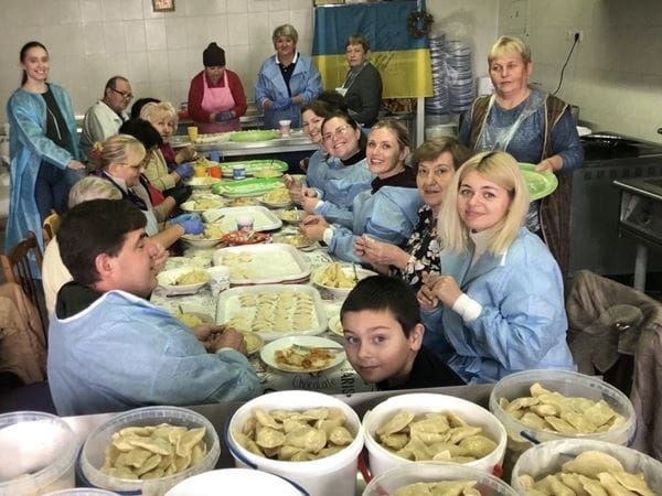 A group of people sitting at a table preparing food