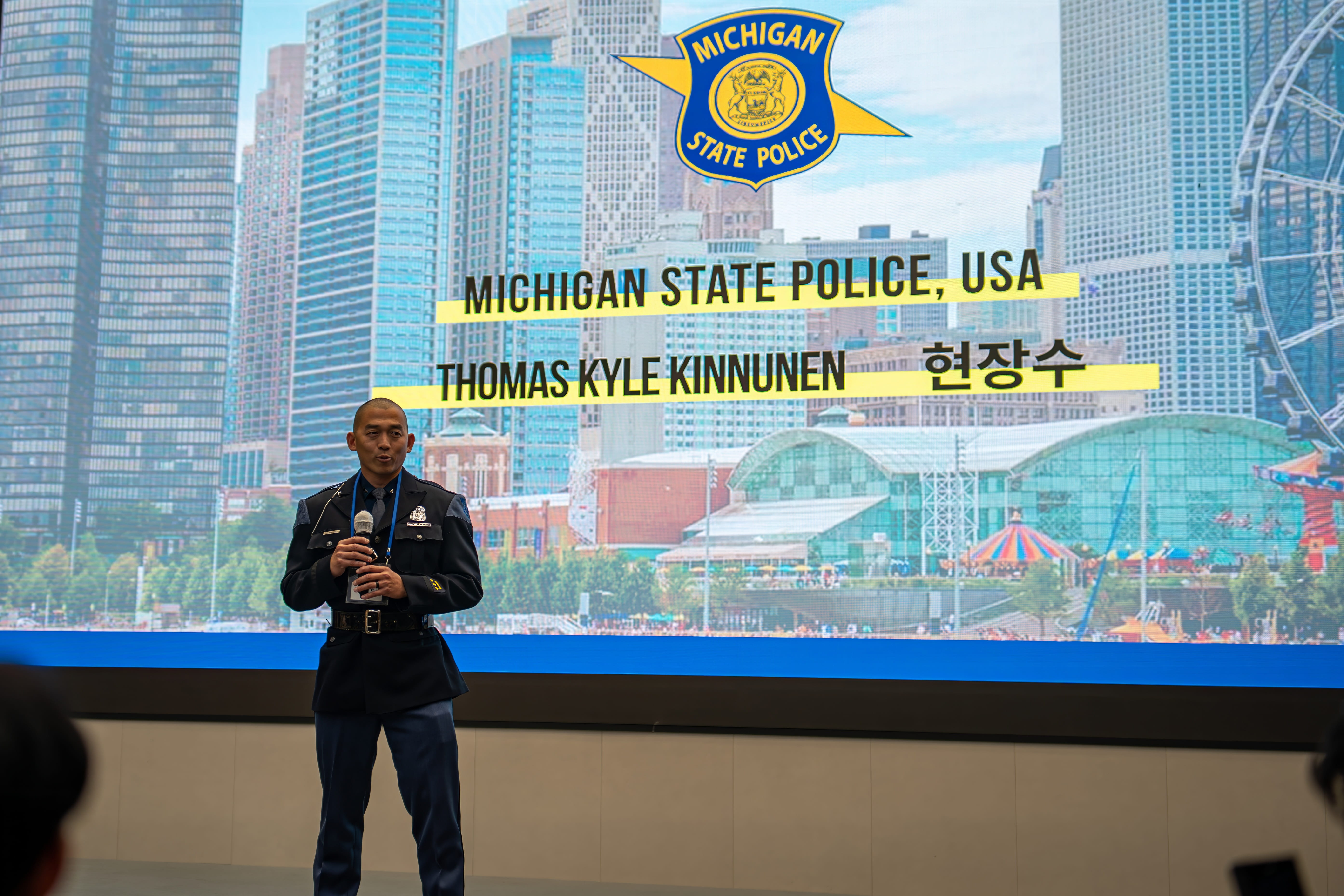 Trooper Tom Kinnunen in Korea in uniform standing on stage at the start of his program