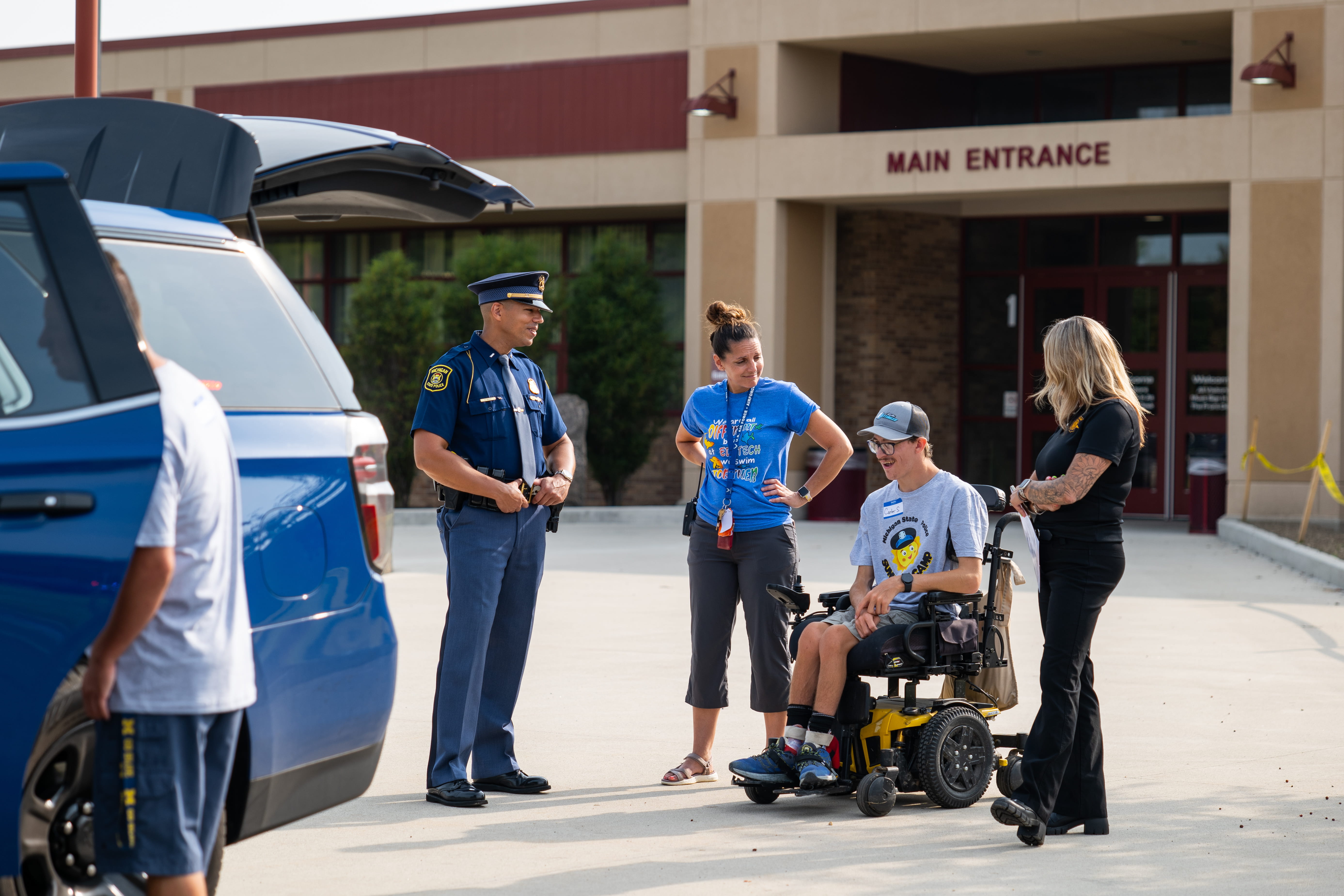 F/Lt. Duane Zook speaking with child in wheelchair outside of a building