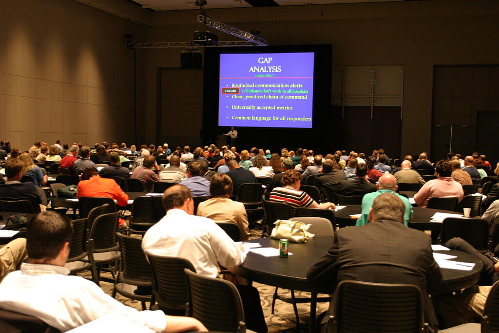 2006 attendees in a session sitting at tables listening to a speaker
