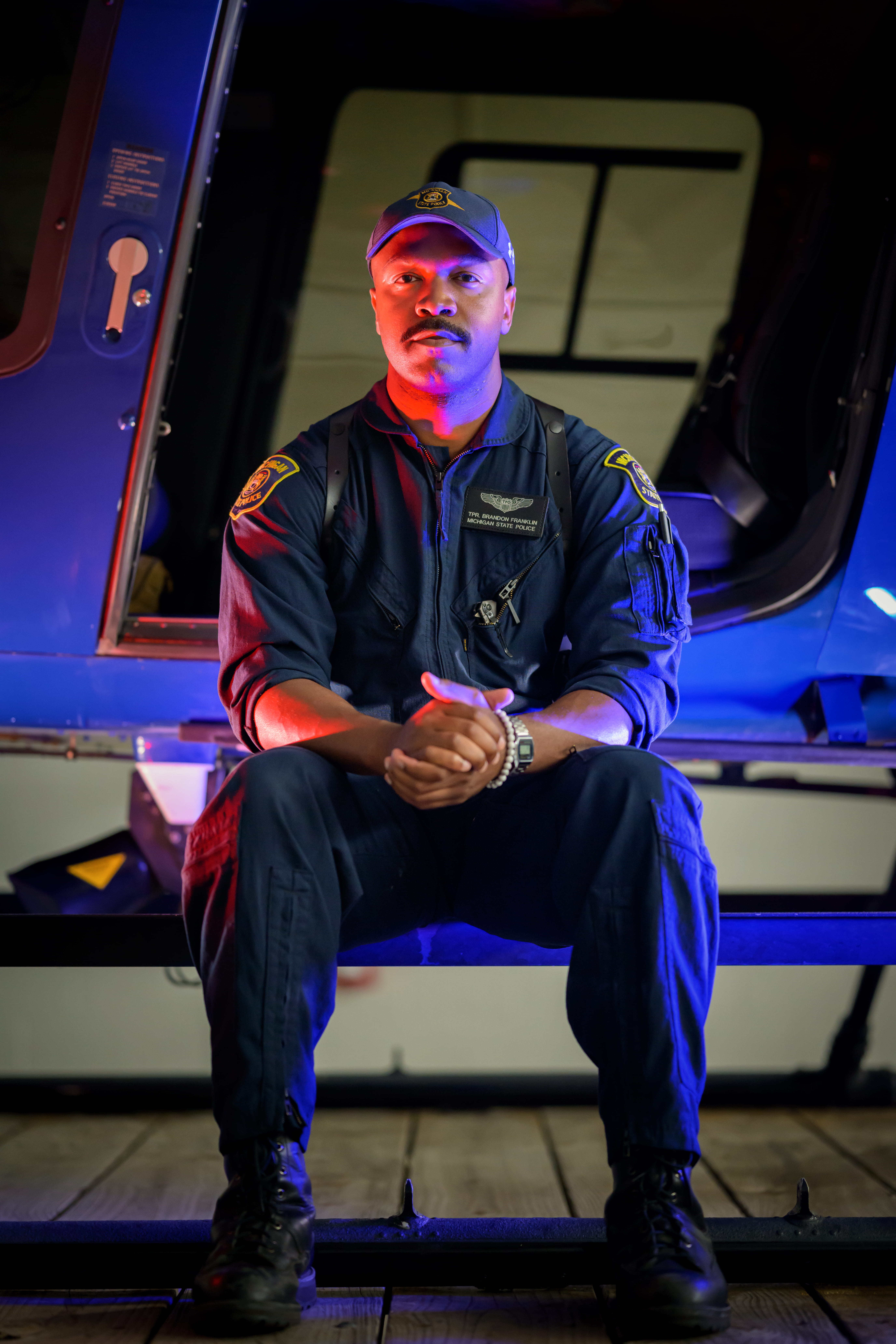 Nightime photo of Tpr. Brandon Franklin sitting near the open door of an MSP helicopter