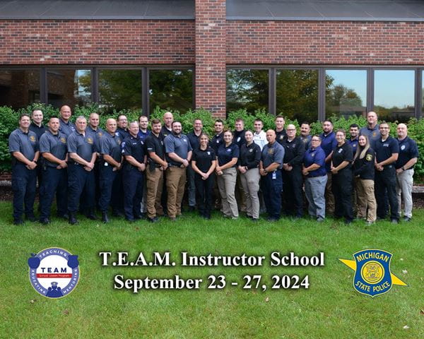 26 officers who graduated from T.E.A.M. school liaison program standing with staff outside of MSP Headquarters
