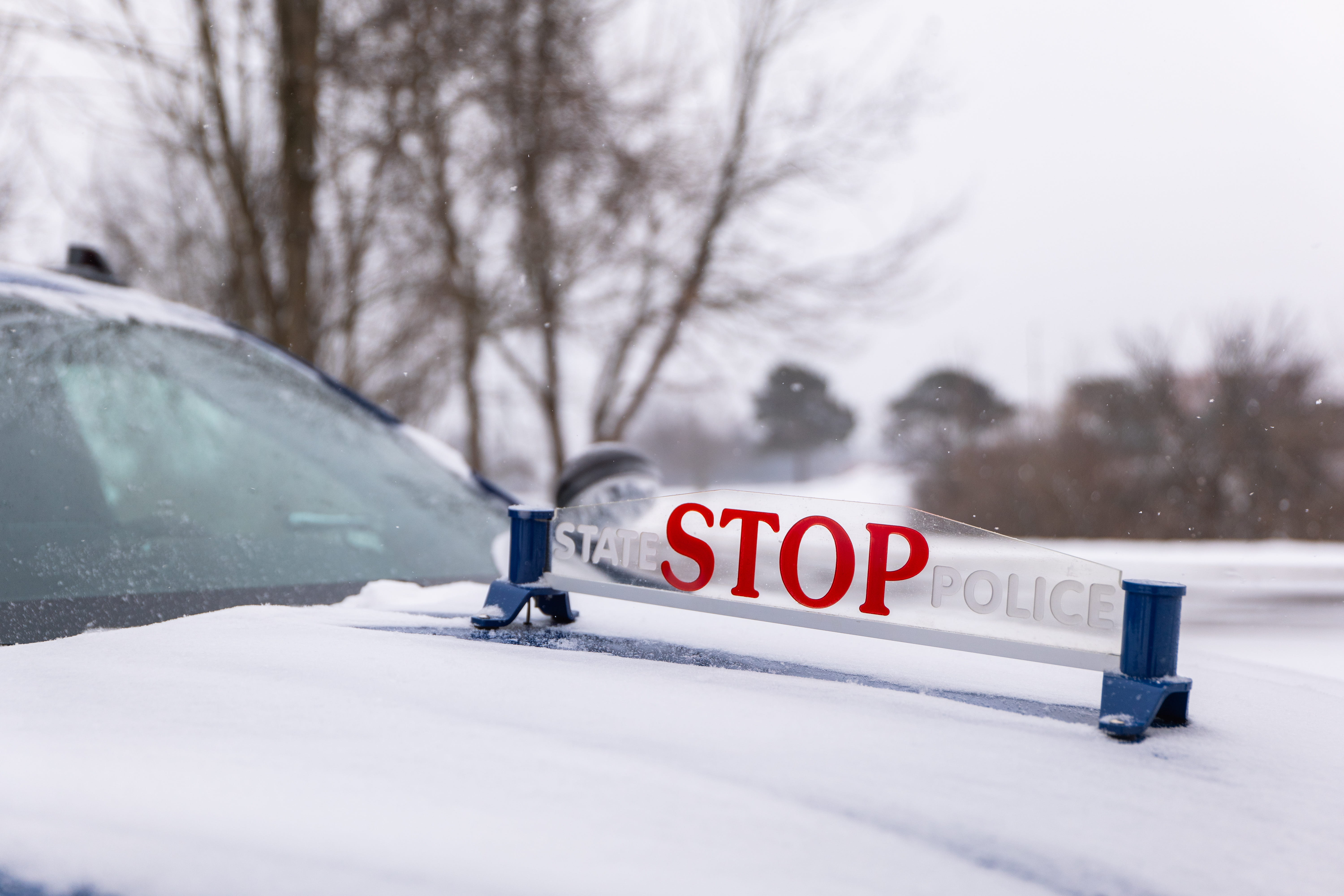 Close-up of Michigan State Police “Stop” placard on hood of patrol car. 