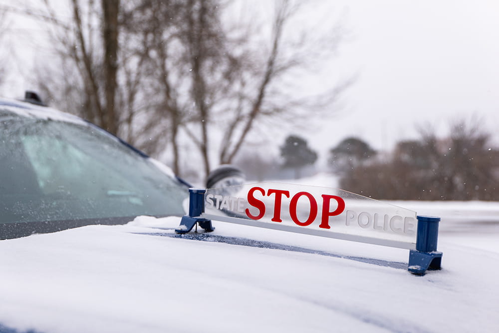 Close-up of Michigan State Police “Stop” placard on hood of patrol car. 