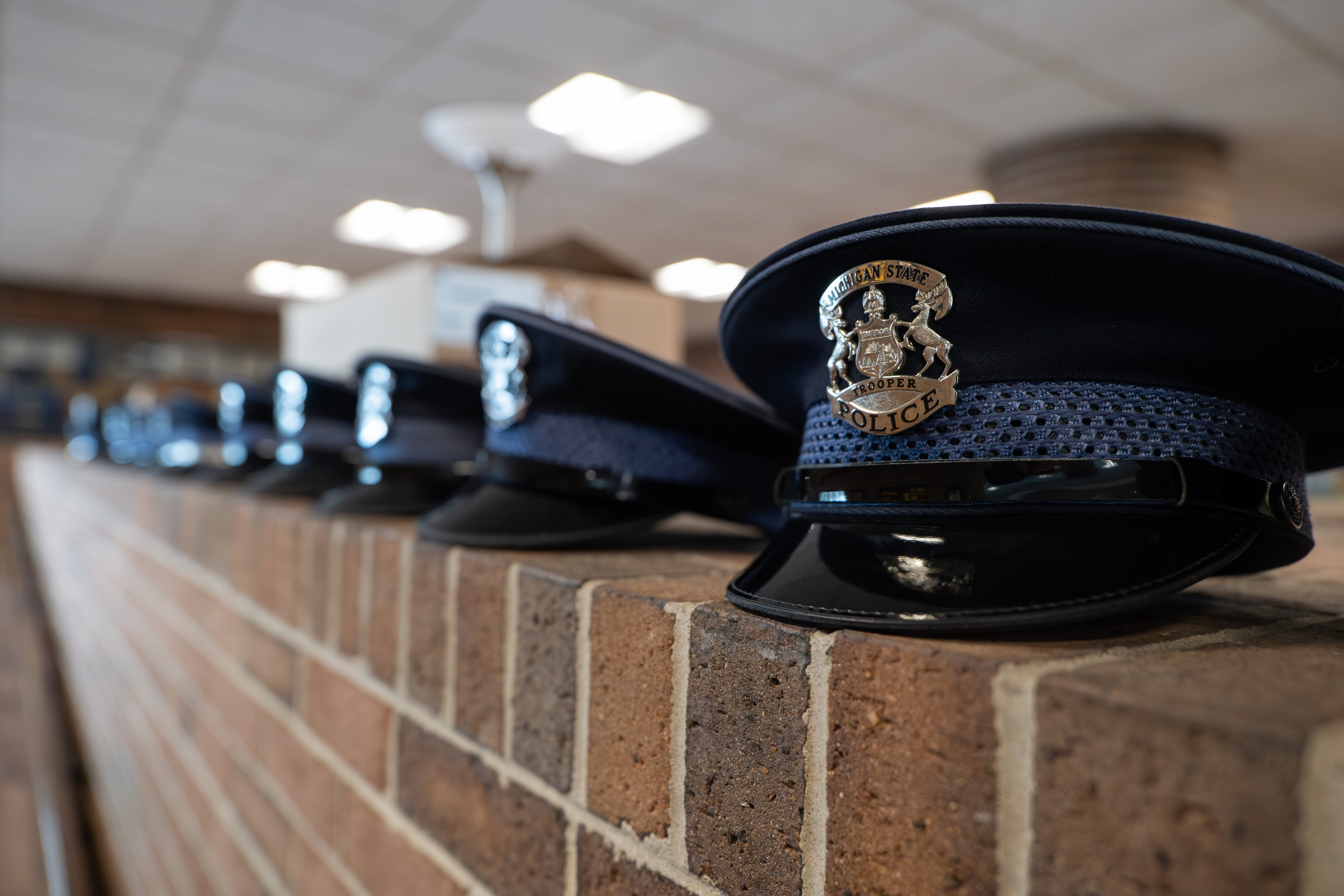 Several trooper caps lined up on brick wall, shown on angle.