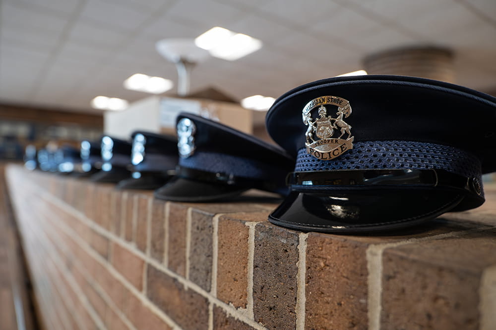 Several trooper caps lined up on brick wall, shown on angle.