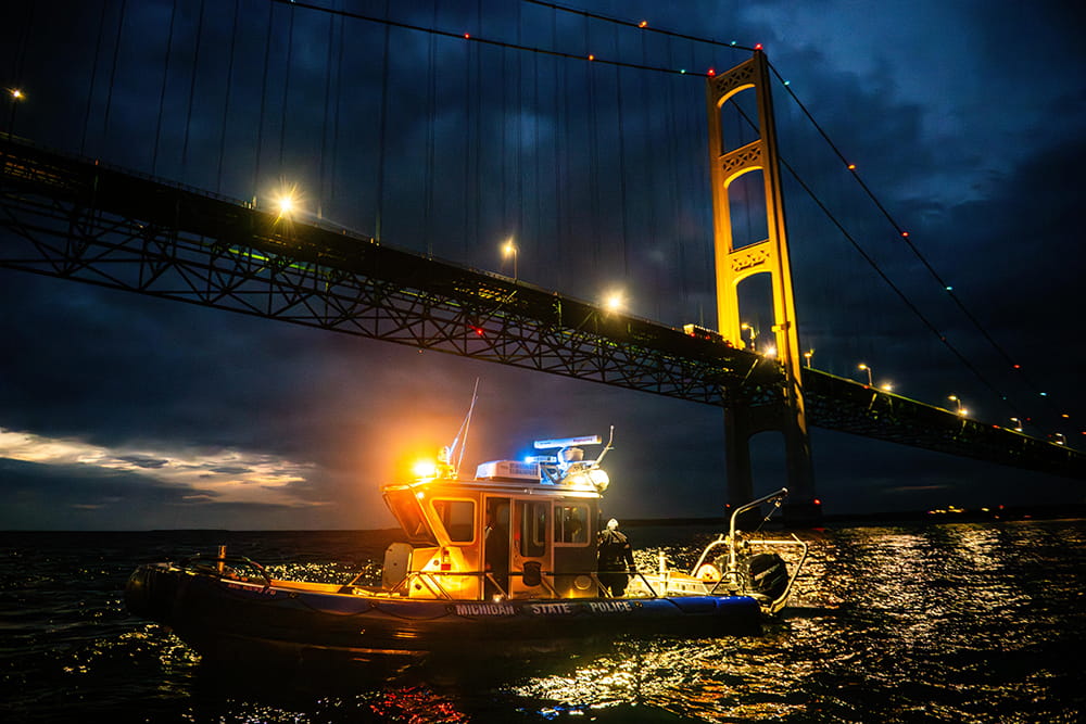 Michigan State Police Marine Services Team boat under Mackinac Bridge, at night.
