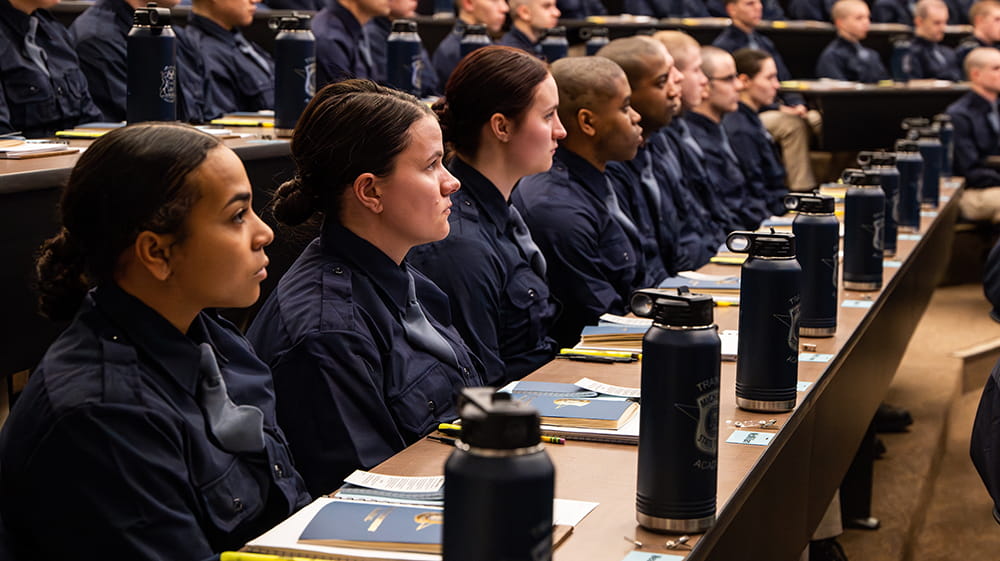 Several recruits sitting in auditorium at trooper recruit school.