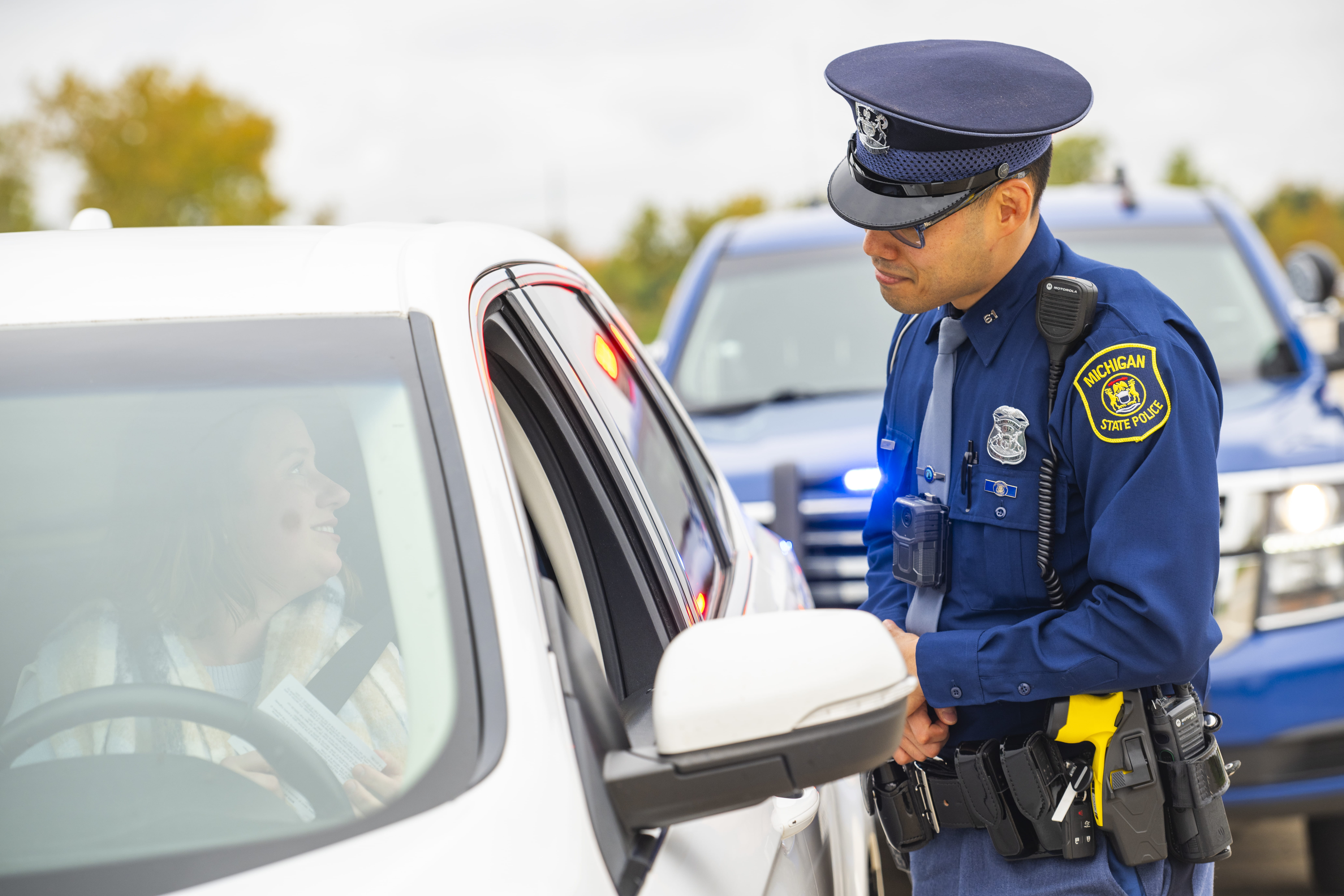 Trooper speaking to driver through car window on a traffic stop. 