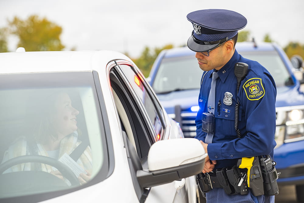 Trooper speaking to driver through car window on a traffic stop. 