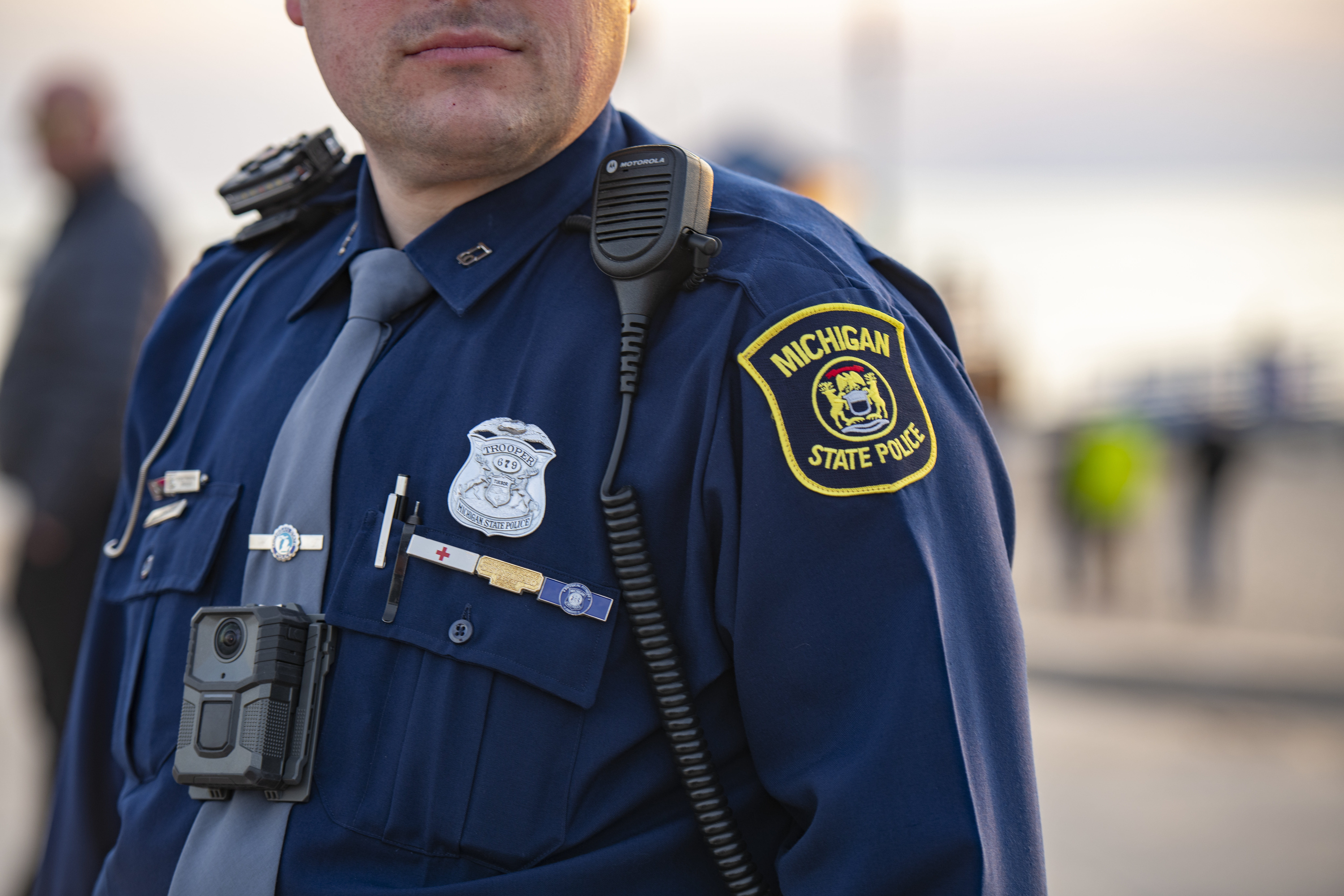 Close-up of trooper badge, radio, and shoulder patch.