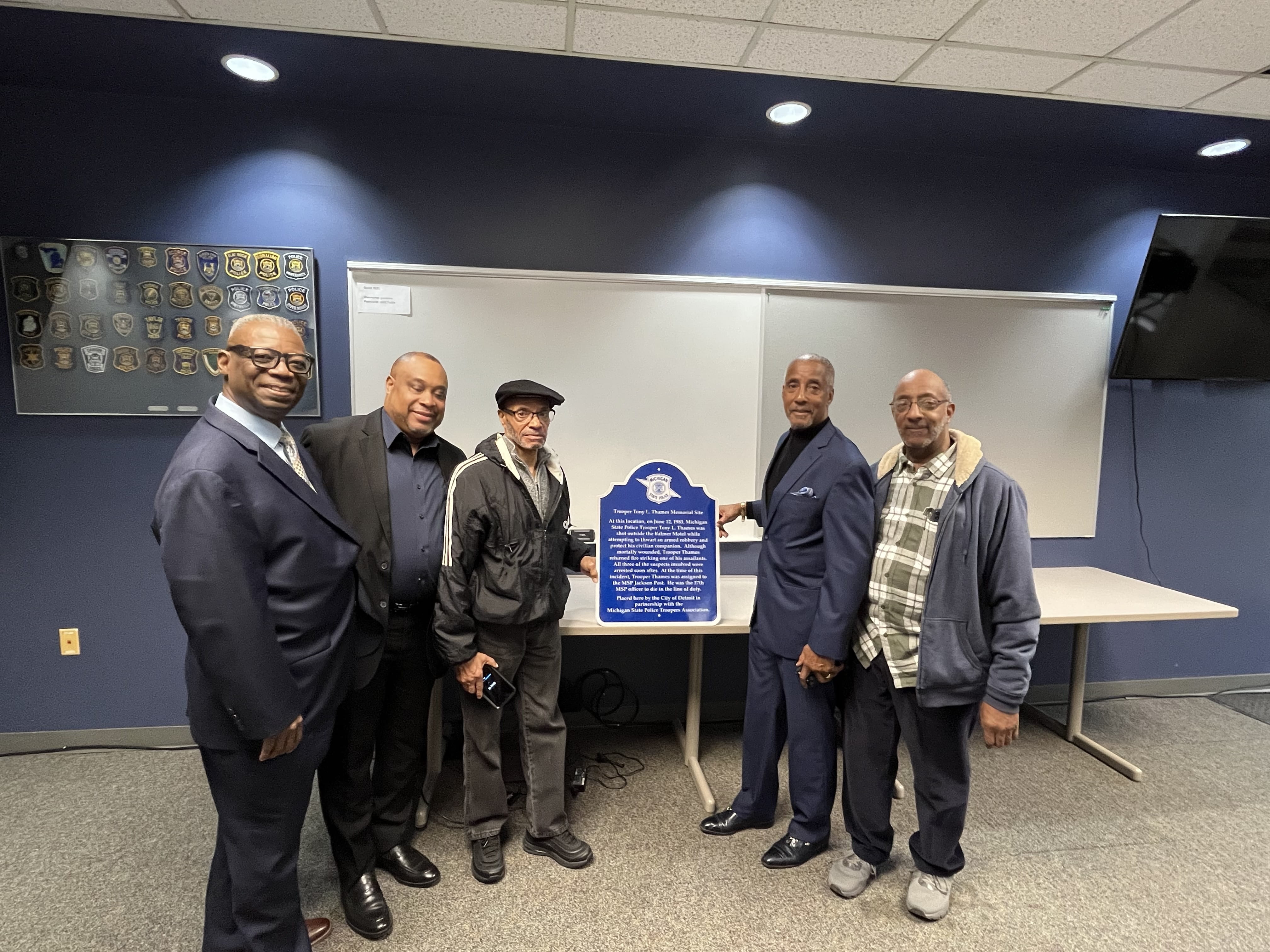 Relatives and friends of fallen Jackson Post Tpr. Tony L. Thames poses for a photo with a sign bearing his name after a memorial dedication at the Metro South Post in Taylor, Nov. 19, 2024. 