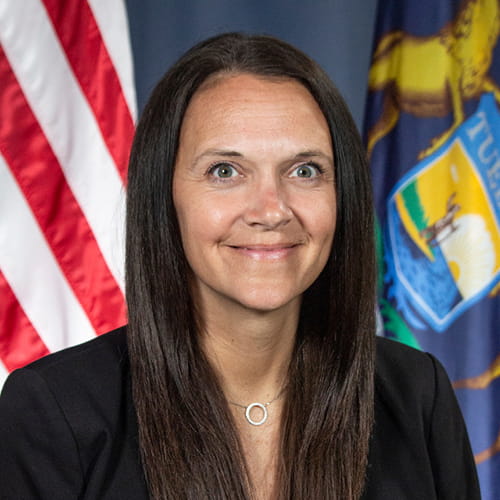 Brandy Walkington Head shot with USA and Michigan flags in the background
