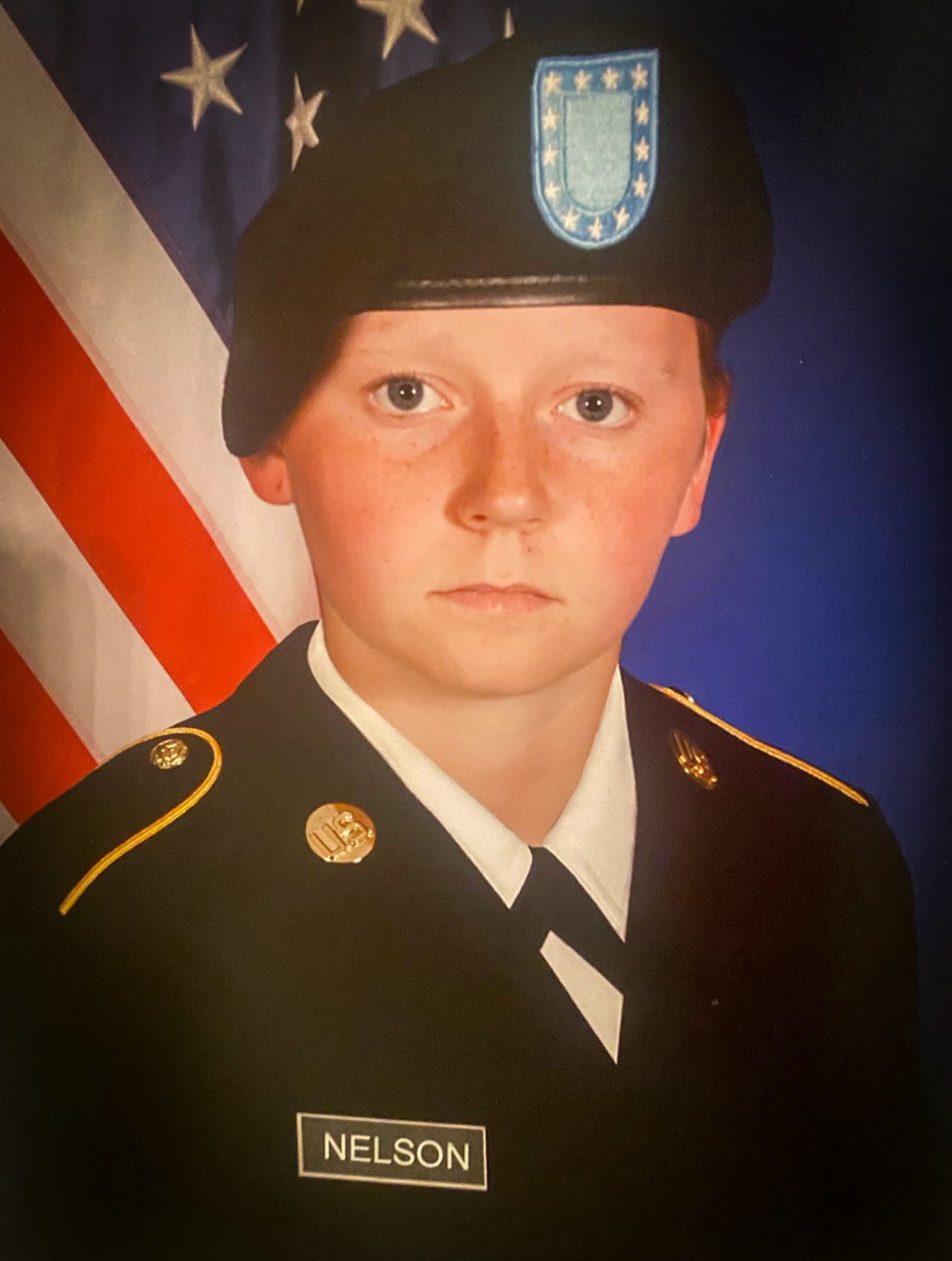 Alexis Nelson wearing a military uniform while posing in front of the American flag