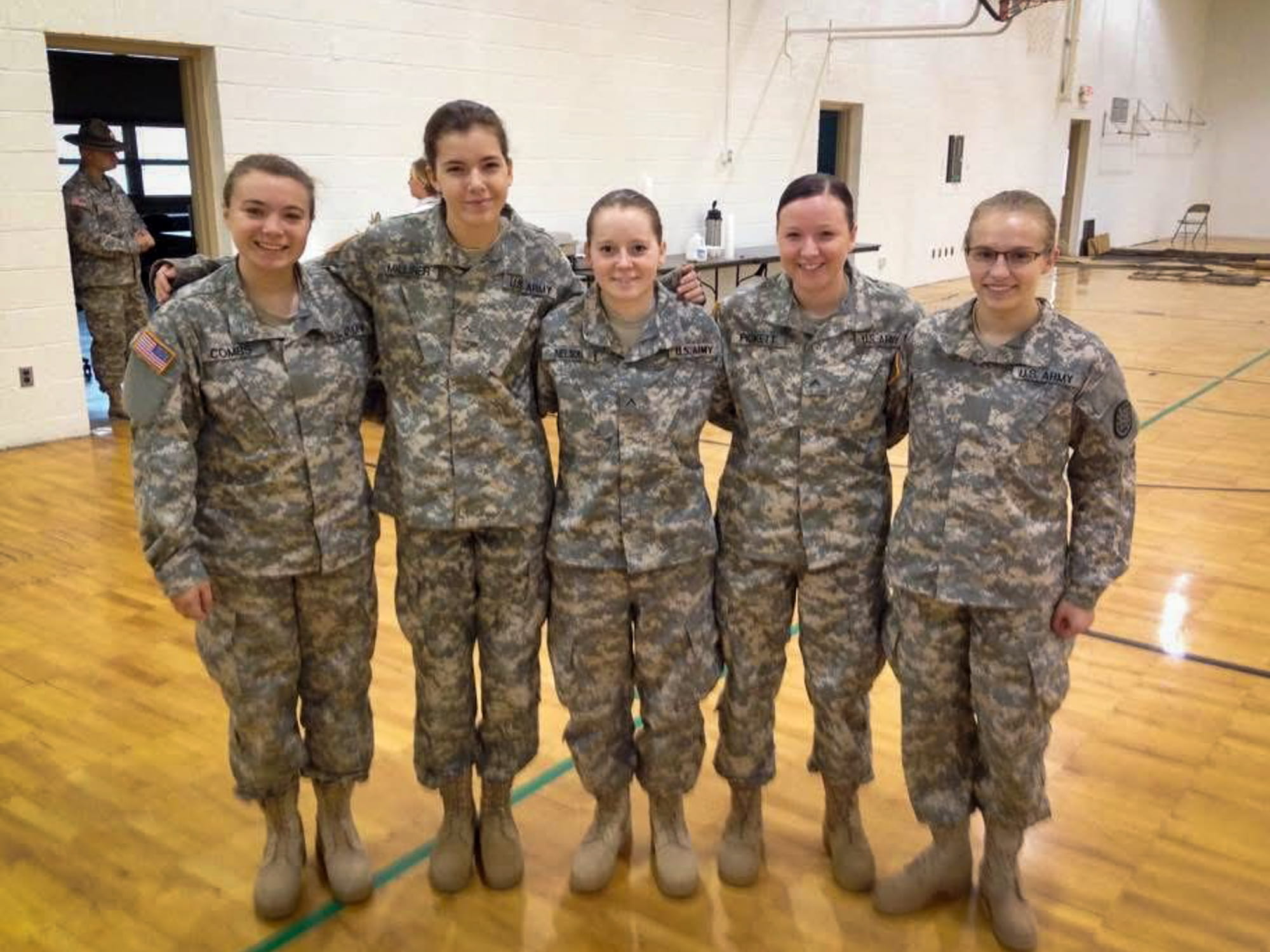 Alexis Nelson takes a photo with four female National Guard soldiers inside a gymnasium