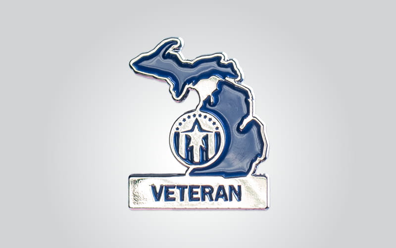Image of a lapel pin, shaped like the State of Michigan with the MVAA logo and the word Veteran across the bottom