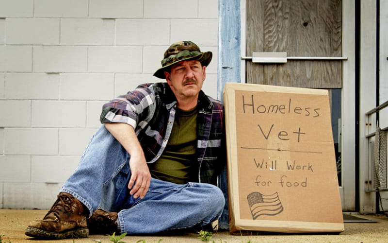 Homeless Veteran holding a sign that reads, "Homeless Vet / Will Work for food"
