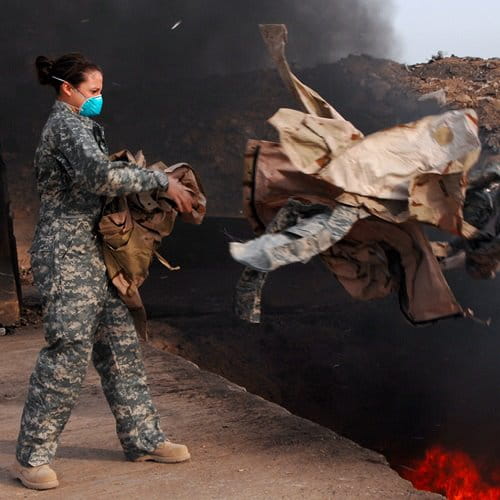 Female soldier throwing items into burn pit