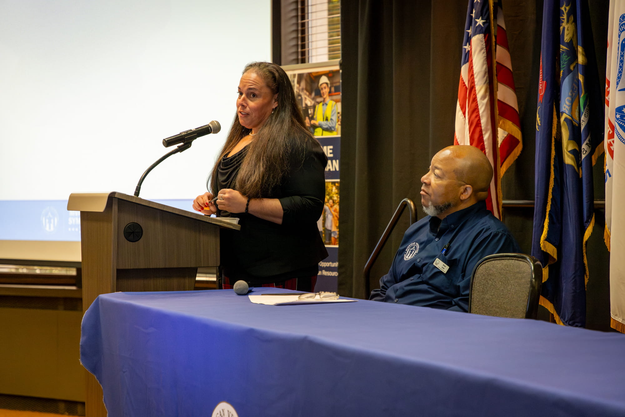 Michigan Veterans Affairs Agency (MVAA) Community Analyst addresses attendees and introduces MVAA Director Brian L. Love at the first Community Outreach and Regional Engagement (CORE) Symposium, Wednesday, Sept. 18