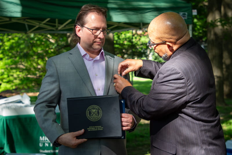Michigan Veterans Affairs Agency Director Brian L. Love pins Distinguished Service Medal on Dr. Chris Petras for his advocacy for World War I veterans.