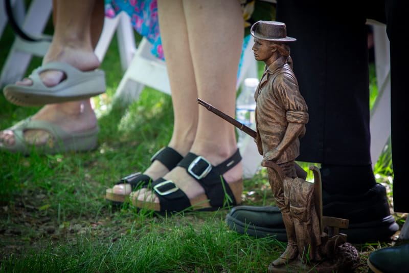 Minute Man statue from the Michigan Army National Guard sits at the feet of Dr. Chris Petras at the Michigan State University Memorial Grove Rededication Ceremony.