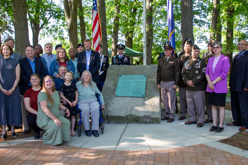 Attendees of the May 23, 2024, Michigan State University Memorial Grove Rededication Ceremony pose in front of newly renovated Memorial Grove.