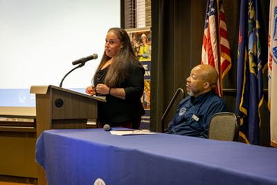 Michigan Veterans Affairs Agency (MVAA) Community Analyst addresses attendees and introduces MVAA Director Brian L. Love at the first Community Outreach and Regional Engagement (CORE) Symposium, Wednesday, Sept. 18