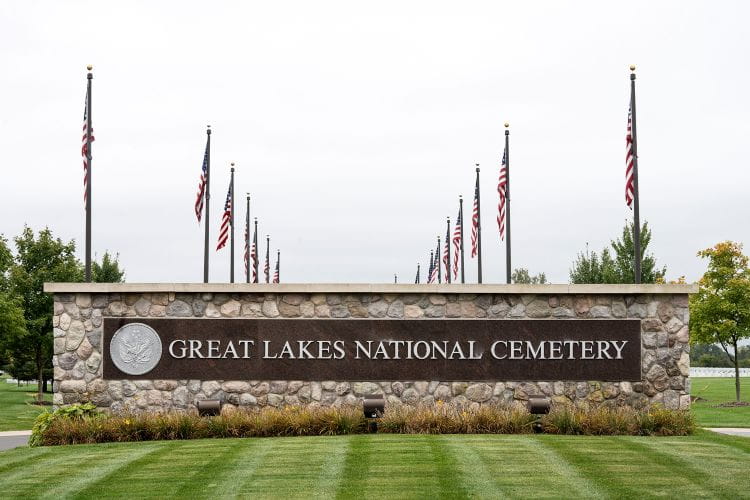Entrance to Great Lakes National Cemetery, with American flags lining the roadway.