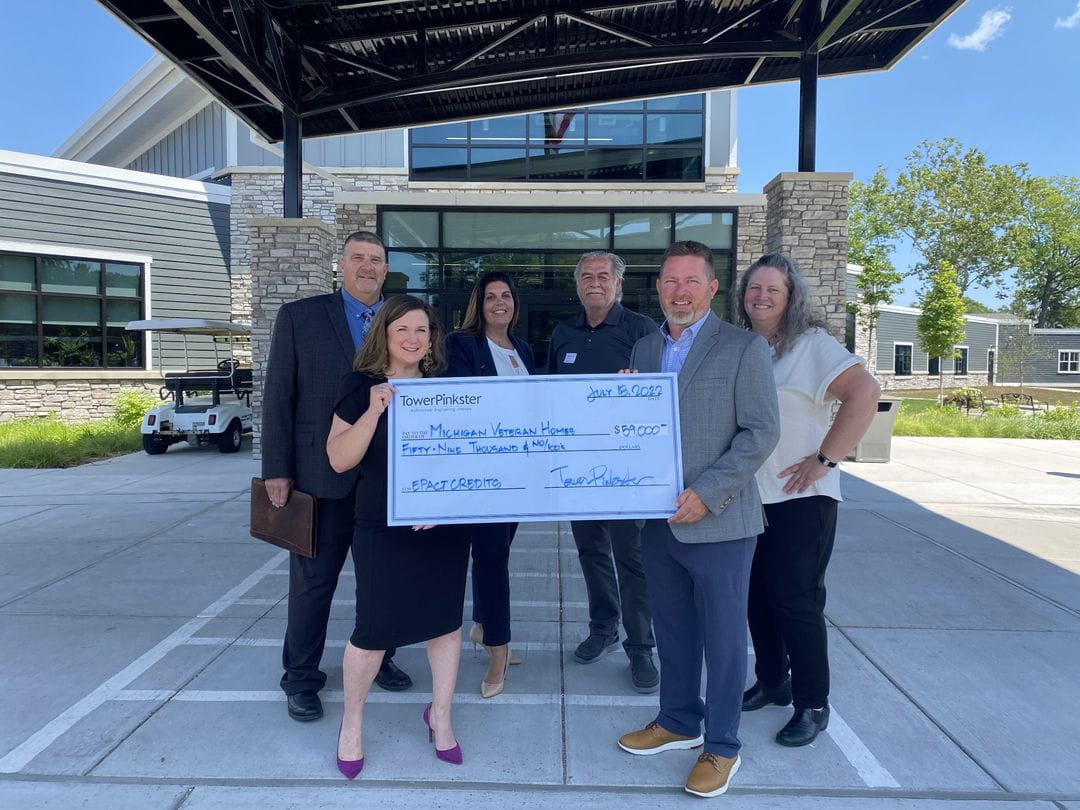 TowerPinkster and MVH Staff hold a presentation check for $59,000 in front of the entrance to MVH at Grand Rapids