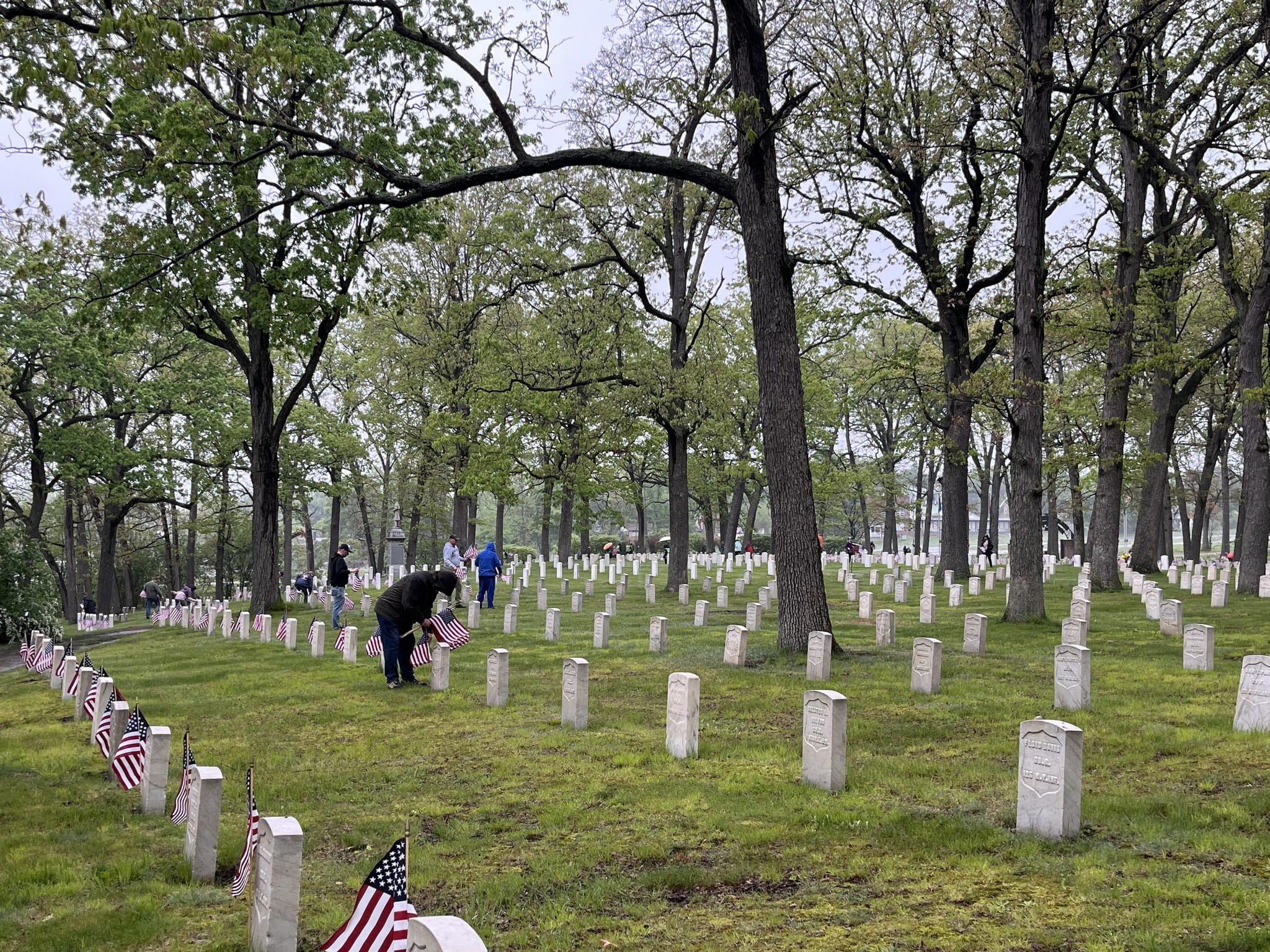 people placing flags in cemetery